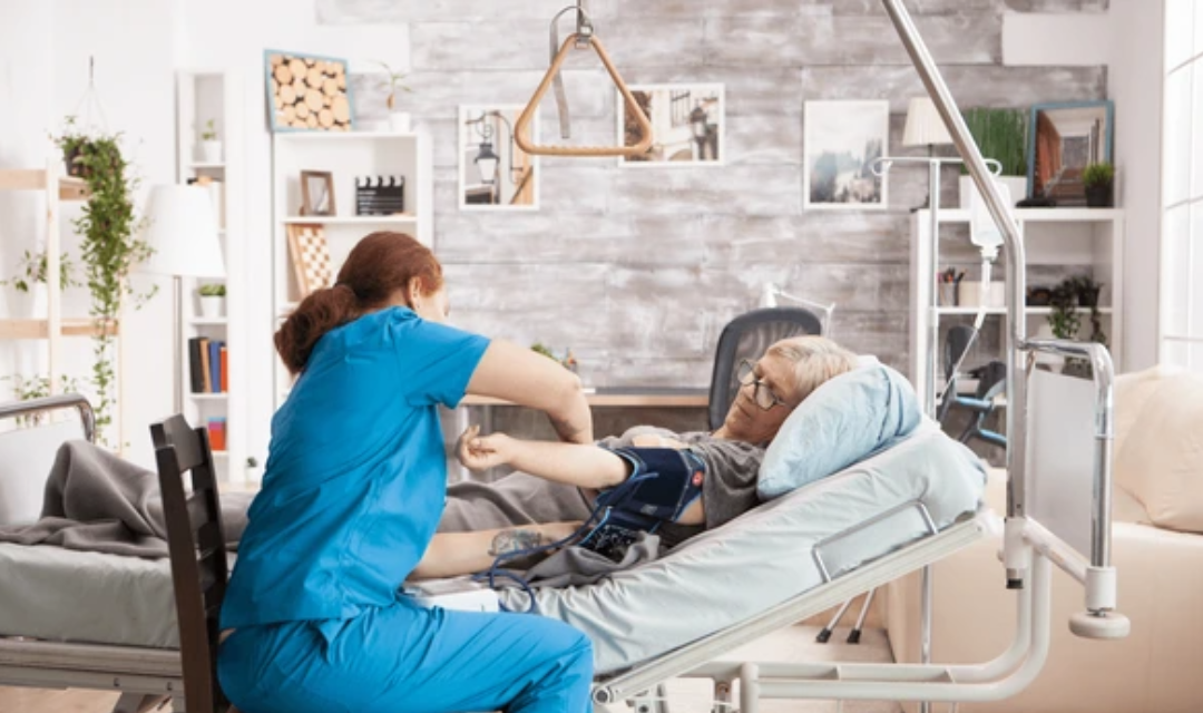 Home caregiver assisting elderly woman with medical bed and safety equipment – how to care for elderly at home