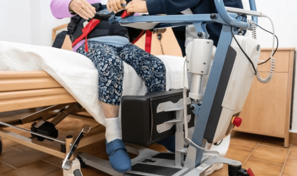 Patient sit to stand lift assisting elderly man with safe and comfortable transfer at home