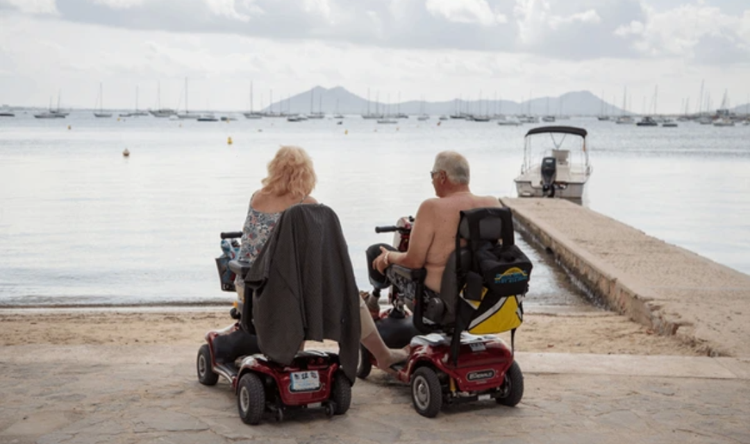 Happy senior couple enjoying outdoor summer activities for seniors on a boardwalk with mobility aids